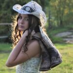 McKenna Faith Winters wearing a cowgirl hat and has cowboy boots over her shoulder